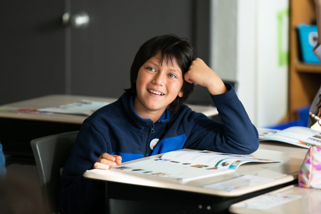 Élève souriant à son pupitre lors d'un atelier Carbone Scol'ERE en classe du primaire