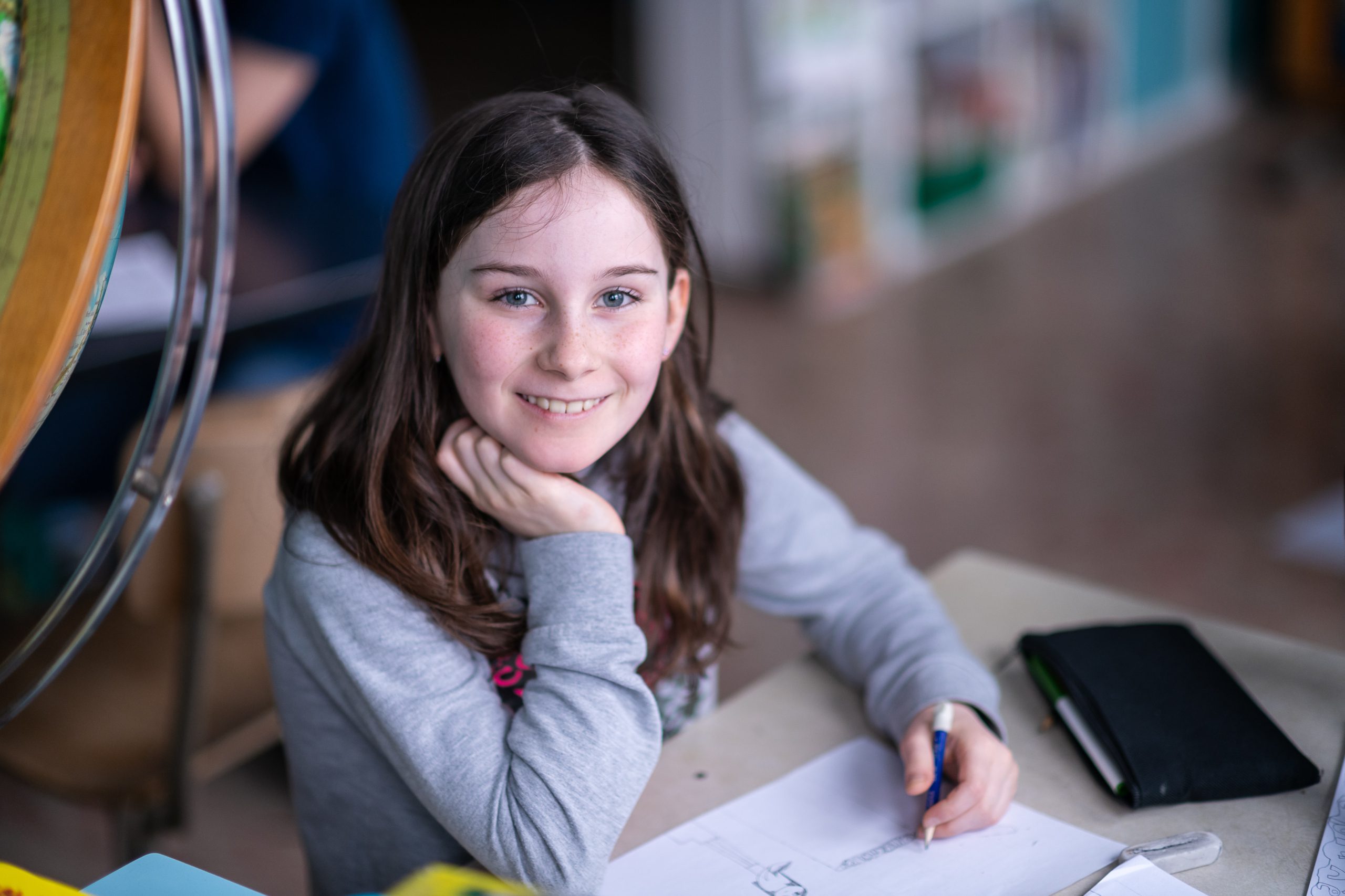 Élève souriante en classe, appuyée sur sa main
